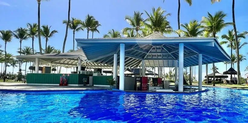 Piscina de resort em Comandatuba com bar central e coqueiros ao redor